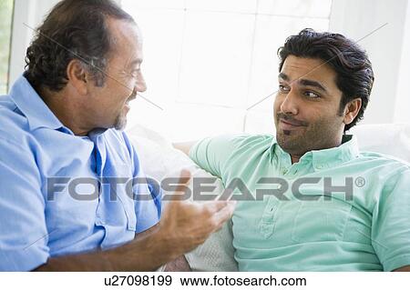 Stock Photo - Two men in living room talking and smiling (high key). Fotosearch