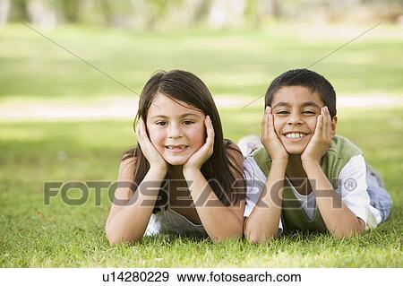 Two young children outdoors lying in park smiling (selective focus) View Large Photo Image Stock Photo - Two young children outdoors lying in park smiling (selective focus). Fotosearch