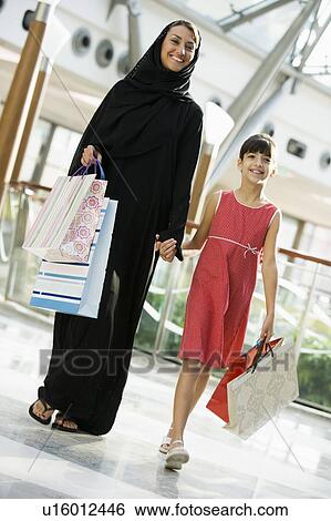 Stock Photograph - Woman and young girl walking in mall smiling (selective focus). Fotosearch