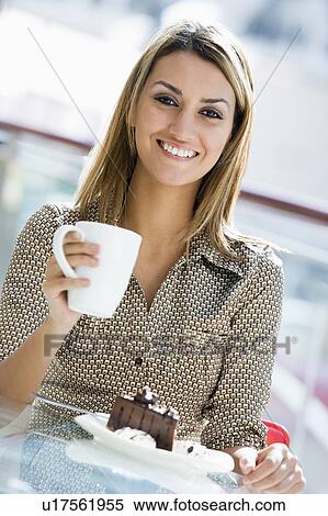 Stock Photography - Woman at restaurant eating dessert and smiling (selective focus). Fotosearch