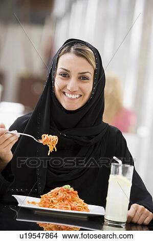 Woman at restaurant eating spaghetti and smiling (selective focus) View Large Photo Image Picture - Woman at restaurant eating spaghetti and smiling (selective focus). Fotosearch