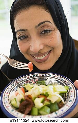 Picture - Woman holding bowl of salad and smiling (high key/selective focus). Fotosearch