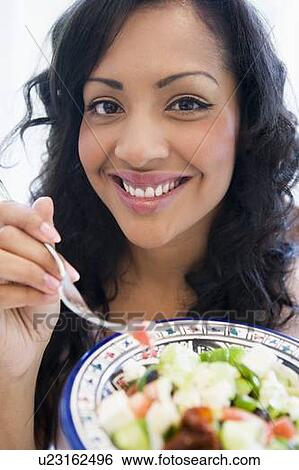 Stock Photograph - Woman holding bowl of salad and smiling (high key/selective focus). Fotosearch