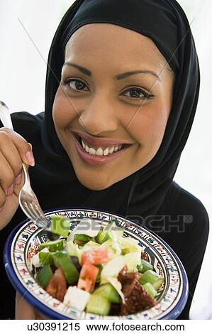 Stock Photography - Woman holding bowl of salad and smiling (studio shot/selective focus). Fotosearch