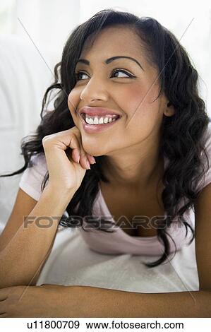 Stock Photo - Woman in living room smiling (high key/selective focus). Fotosearch