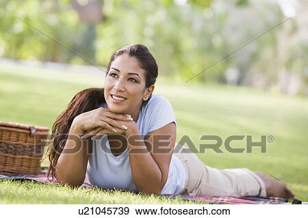 Woman lying outdoors at park with picnic basket smiling (selective focus) View Large Photo Image Stock Photo - Woman lying outdoors at park with picnic basket smiling (selective focus). Fotosearch