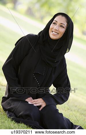 Woman sitting outdoors in park smiling (selective focus) View Large Photo Image Stock Image - Woman sitting outdoors in park smiling (selective focus). Fotosearch