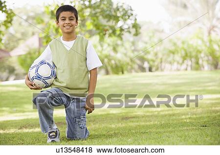 Young boy outdoors at park holding ball and smiling (selective focus) View Large Photo Image Stock Photo - Young boy outdoors at park holding ball and smiling (selective focus). Fotosearch