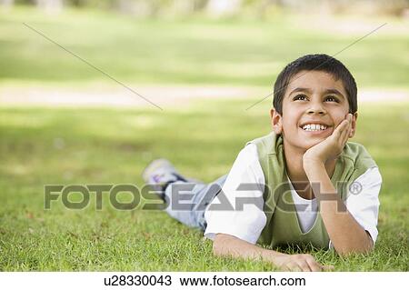 Young boy outdoors lying in grass and smiling (selective focus) View Large Photo Image Stock Image - Young boy outdoors lying in grass and smiling (selective focus). Fotosearch