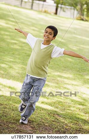 Stock Image - Young boy outdoors playing at park and smiling (selective focus). Fotosearch