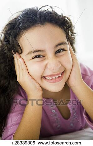 Stock Photography - Young girl in living room smiling (high key/selective focus). Fotosearch