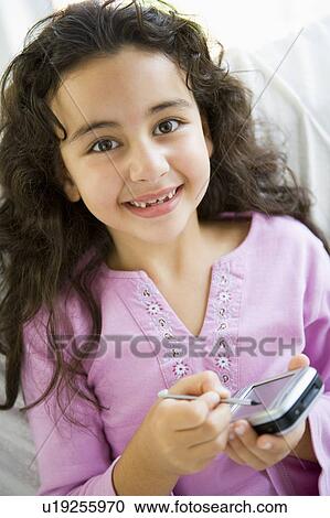 Young girl in living room with personal digital assistant smiling (high key) View Large Photo Image Stock Image - Young girl in living room with personal digital assistant smiling (high key). Fotosearch