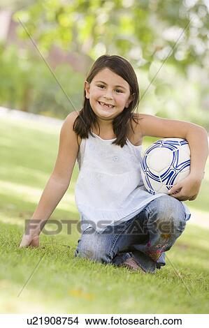 Young girl outdoors at park holding ball and smiling (selective focus) View Large Photo Image Picture - Young girl outdoors at park holding ball and smiling (selective focus). Fotosearch
