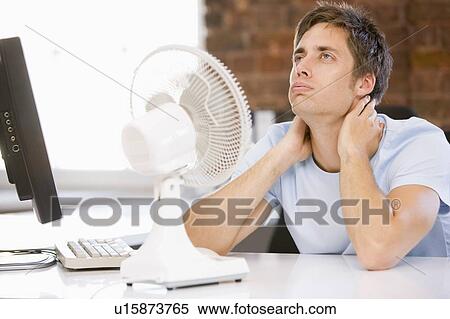 Businessman in office with computer and fan cooling off View Large Photo Image Stock Photography - Businessman in office with computer and fan cooling off. Fotosearch