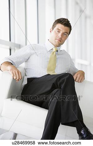 Businessman sitting in office lobby View Large Photo Image Stock Photo - Businessman sitting in office lobby. Fotosearch