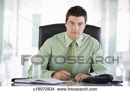 Picture - Businessman sitting in office with personal organizer. Fotosearch