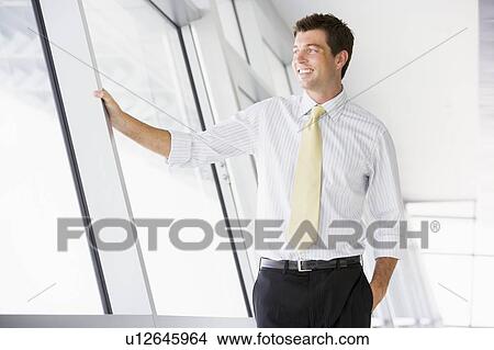 Picture - Businessman standing in corridor smiling. Fotosearch