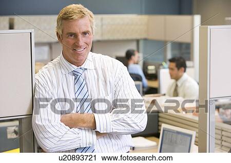 Businessman standing in cubicle smiling View Large Photo Image Stock Image - Businessman standing in cubicle smiling. Fotosearch
