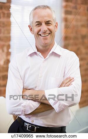 Businessman standing in office laughing View Large Photo Image Stock Photography - Businessman standing in office laughing. Fotosearch