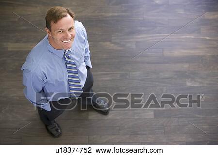 Stock Image - Businessman standing indoors smiling. Fotosearch