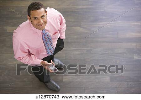 Businessman standing indoors with cellular phone smiling View Large Photo Image Stock Image - Businessman standing indoors with cellular phone smiling. Fotosearch