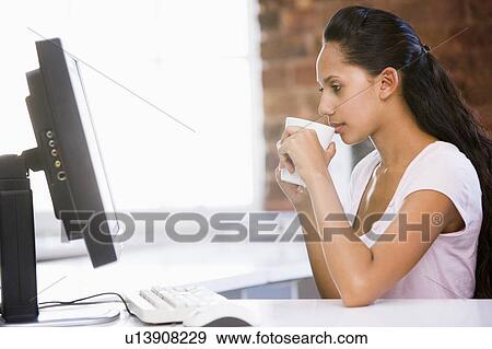 Businesswoman in office drinking coffee and looking at computer View Large Photo Image Stock Photo - Businesswoman in office drinking coffee and looking at computer. Fotosearch