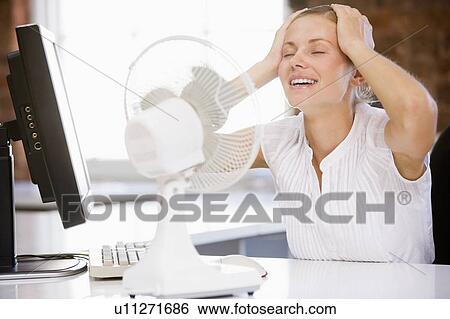 Businesswoman in office with computer and fan cooling off View Large Photo Image Stock Photograph - Businesswoman in office with computer and fan cooling off. Fotosearch