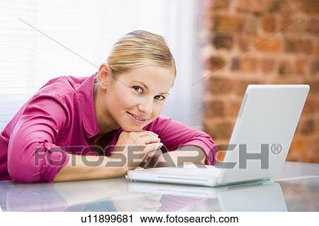 Businesswoman sitting in office with laptop smiling View Large Photo Image Stock Image - Businesswoman sitting in office with laptop smiling. Fotosearch