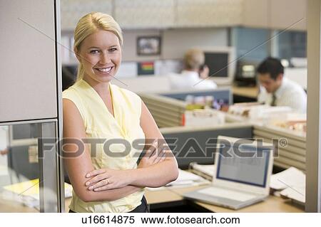 Stock Photography - Businesswoman standing in cubicle smiling. Fotosearch