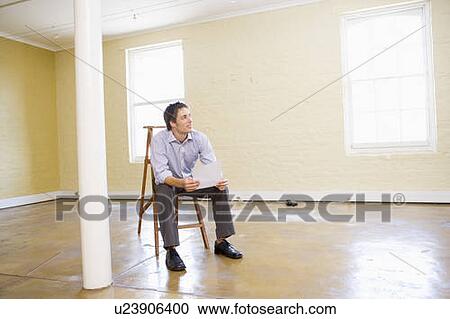 Man sitting on ladder in empty space holding paper View Large Photo Image Stock Image - Man sitting on ladder in empty space holding paper. Fotosearch