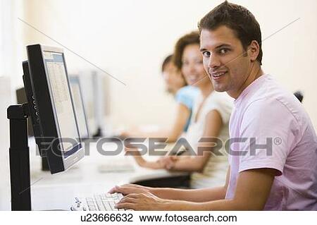 Three people sitting in computer room typing and smiling View Large Photo Image Stock Image - Three people sitting in computer room typing and smiling. Fotosearch