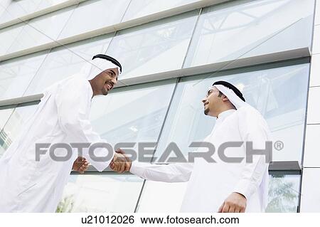 Two businessmen outdoors by building shaking hands and smiling View Large Photo Image Stock Photograph - Two businessmen outdoors by building shaking hands and smiling. Fotosearch