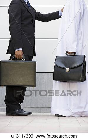Stock Photo - Two businessmen standing outdoors with briefcases. Fotosearch