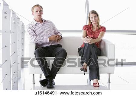 Two businesspeople sitting in office lobby smiling View Large Photo Image Stock Image - Two businesspeople sitting in office lobby smiling. Fotosearch