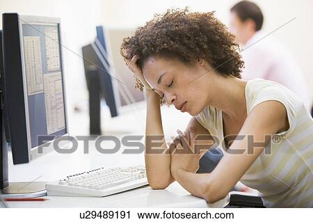 Stock Image - Woman in computer room sleeping. Fotosearch
