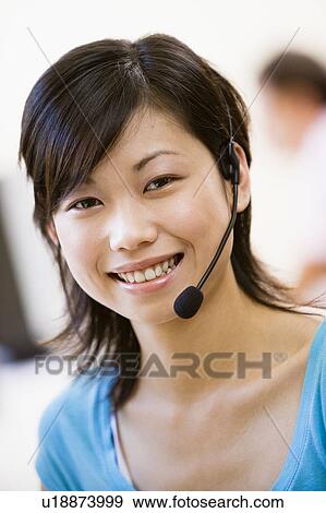 Stock Photo - Woman wearing headset indoors smiling. Fotosearch