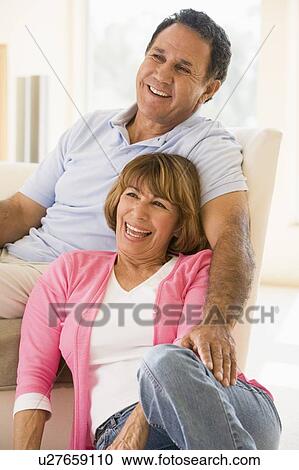 Stock Image - Couple in living room smiling. Fotosearch