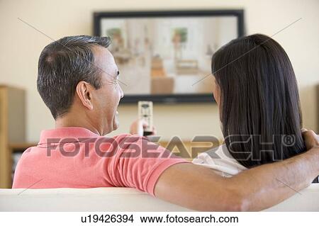 Picture - Couple in living room watching television laughing. Fotosearch
