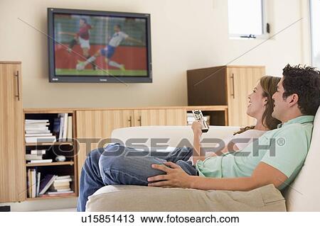 Stock Image - Couple in living room watching television. Fotosearch