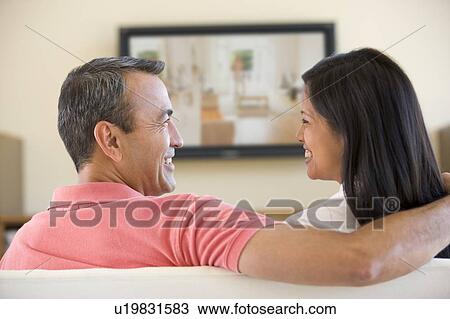 Couple in living room watching television smiling View Large Photo Image Stock Image - Couple in living room watching television smiling. Fotosearch