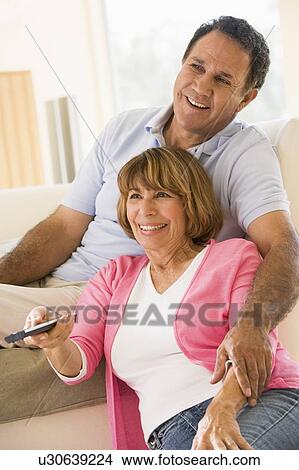 Couple in living room with remote control smiling View Large Photo Image Picture - Couple in living room with remote control smiling. Fotosearch