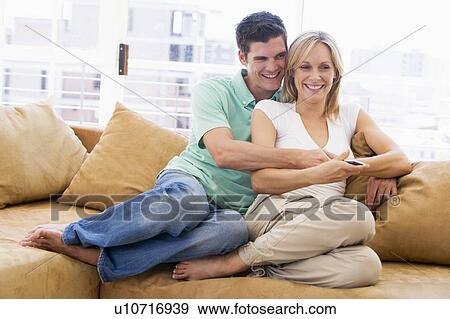 Couple in living room with remote control smiling View Large Photo Image Stock Photo - Couple in living room with remote control smiling. Fotosearch