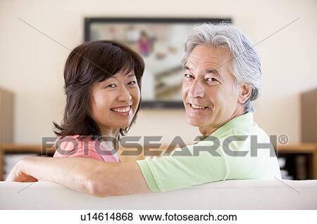 Stock Photo - Couple watching television smiling. Fotosearch