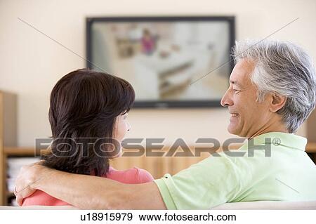 Stock Photo - Couple watching television smiling. Fotosearch