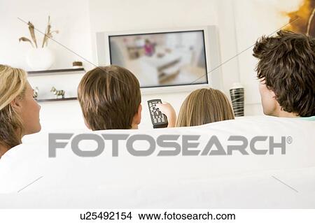 Picture - Family in living room with remote control and flat screen television. Fotosearch