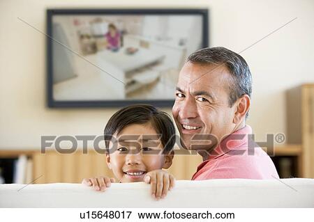 Man and young boy in living room with flat screen television smiling View Large Photo Image Stock Photo - Man and young boy in living room with flat screen television smiling. Fotosearch