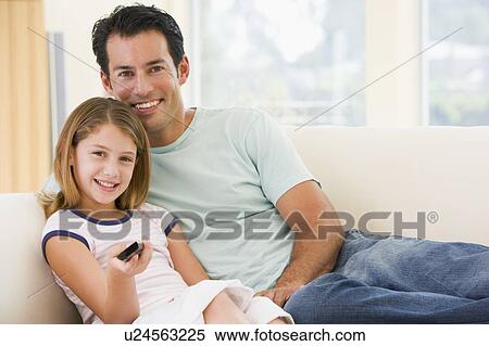 Stock Photography - Man and young girl in living room with remote control smiling. Fotosearch