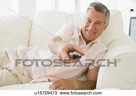 Man in living room using remote control smiling View Large Photo Image Stock Image - Man in living room using remote control smiling. Fotosearch