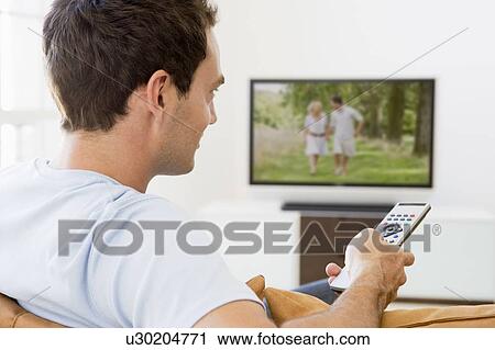 Man in living room watching television View Large Photo Image Stock Image - Man in living room watching television. Fotosearch