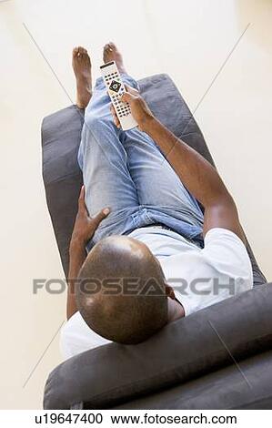 Man sitting in chair using remote control View Large Photo Image Stock Image - Man sitting in chair using remote control. Fotosearch